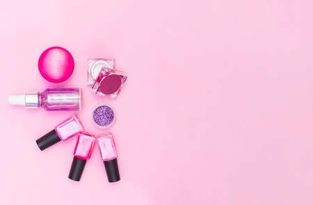 A set of cosmetics for manicure and pedicure on a pink and purple background. Gel varnishes, nail files, nail scissors, pusher, top view.の写真素材