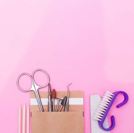 A set of cosmetics for manicure and pedicure on a pink and purple background. Gel varnishes, nail files, nail scissors, pusher, spacers and wire cutters top view.の写真素材