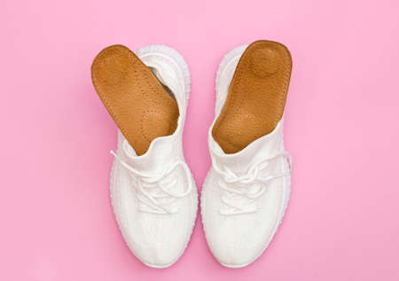 Brown orthopedic insoles for shoes. White sneakers on a pink background.の写真素材