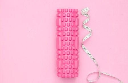 The concept of fitness. Pink fitness roller for training. Centimeter tape. Weight loss. Women's fitness at home.の写真素材