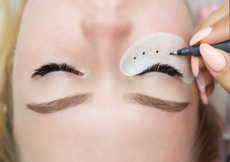 The master of eyelash extension draws a diagram with a black marker on the patch under the eye.の写真素材