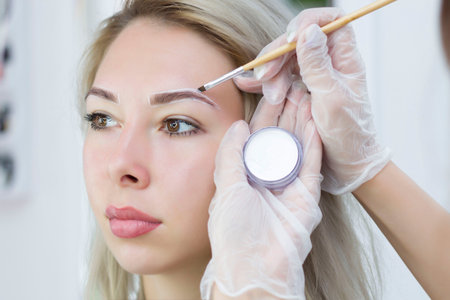 The makeup artist makes notes with a white pencil for eyebrows and paint eyebrows. Professional...