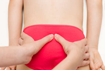 The pelvis of an elementary-age girl is manipulated by an osteopath-an alternative treatment. Displacement of the pelvic bones.の写真素材