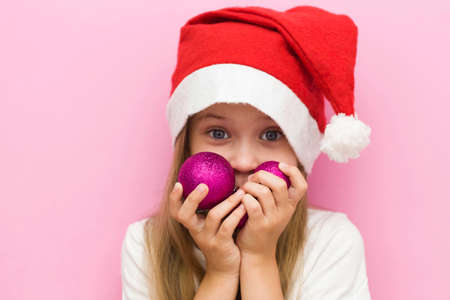 Christmas Eve! A cheerful child in a Christmas hat on a pink background.の写真素材