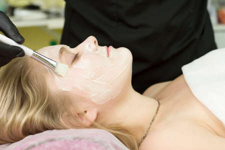 young woman is applied with a brush to the mask on the face. Procedure at the cosmetologist. Relaxの写真素材