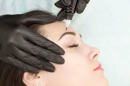 Permanent makeup. Permanent eyebrow tattoo. Cosmetologist applying permanent makeup on eyebrows -...