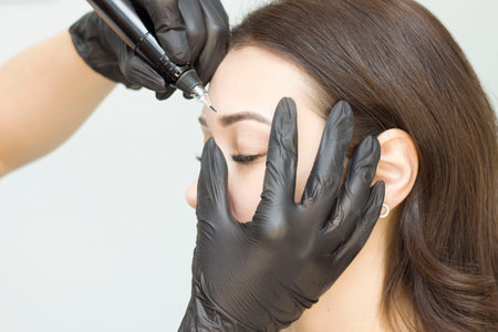 Permanent makeup. Permanent eyebrow tattoo. Cosmetologist applying permanent makeup on eyebrows - eyebrow tattoos. Tattooing. Microblading.の写真素材