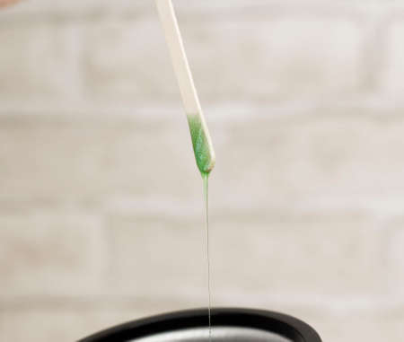 close up of a pipette dripping green paint on a white backgroundの写真素材