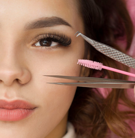 Eyelash Extension Procedure. A woman's eye with long eyelashes. Eyelashes, close-up, macro, selective focus. Tweezers. Beautiful girl on eyelash extension procedureの写真素材