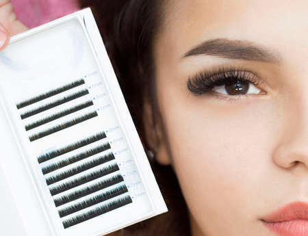 Beautiful girl on the procedure of eyelash extension Face close-up. Macro. Palette with eyelashes.の写真素材