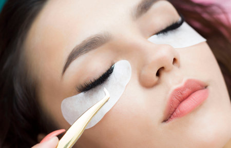 Eyelash extensions. Artificial eyelashes. The girl in the salon is doing an eyelash extension procedure. Close-up.の写真素材