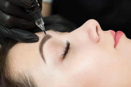 Permanent makeup. Permanent eyebrow tattoo. Cosmetologist applying permanent makeup on eyebrows - eyebrow tattoos. Tattooing. Microblading.の写真素材