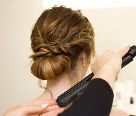 The stylist performs the hairstyle, hair styling in the salon.
