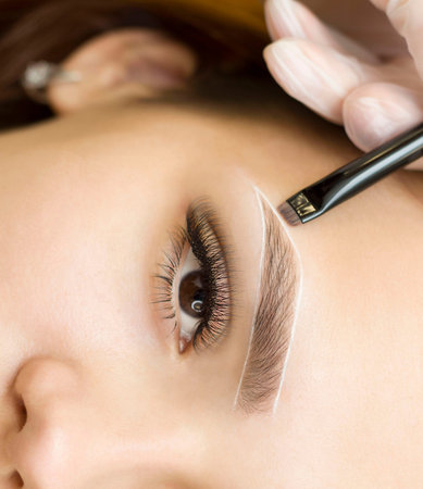 The makeup artist makes markings with a white eyebrow pencil and paints eyebrows. Professional...