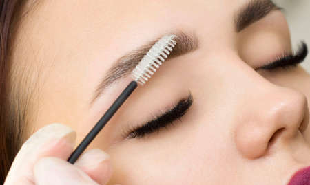 The makeup artist combs his eyebrows with a brush. eyebrow styling. permanent makeup. Coloring with henna paint.の写真素材
