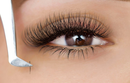Extension of the lower eyelashes. a young woman undergoes a close-up eyelash extension procedure. Tweezers. Down belowの写真素材