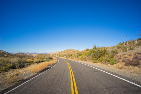 Bending highway road leading into the midst of the Mojave desert in southern California.
