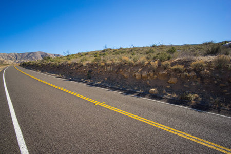 Road cuts into desert hillside in the barren mojave desert.の写真素材