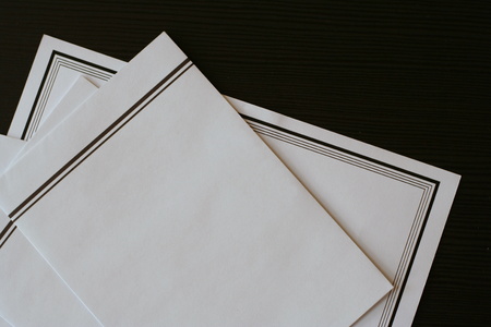 White funeral notice with black border and envelopes prepared on the table for sending.の写真素材