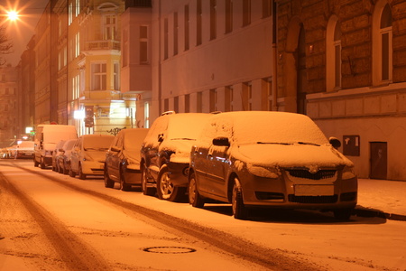 Winter city center street at night with parked cars covered by fresh white snow. Detail on one car. Light with magic rays. New Town, Prague January 2016の写真素材