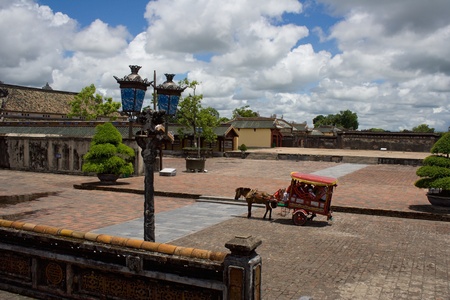 Horse carriage (rig) on the citadel square in Hue royal city, Central Vietnam. Equipage with tourists. Tourist attraction. Summer sunny day with blue sky and few clouds.の写真素材