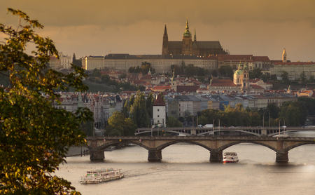 Fall scenery of the Prague Castle - Saint Vitus cathedral, Saint Nicolas Church and bridges over Vltava river and boats. Yellow autumn cityscape.の写真素材