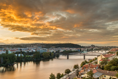 Light sunset over Vltava river with Railway bridge and Prague castle in the background. Moody sky with dramatic clouds. Summer twilight in Prague, Czech Repubicの写真素材