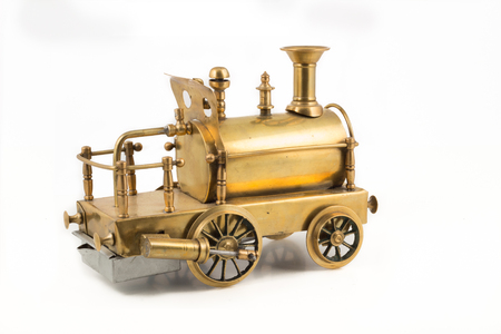Old golden steam locomotive toy on isolated white background.  Antique toy with working steam engine, wheels and bumper.の写真素材