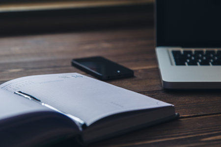 Laptop keyboard and diary on the brown wooden desk