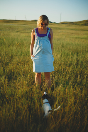 Happy pregnant woman in pink glasses with a dog at sunsetの写真素材