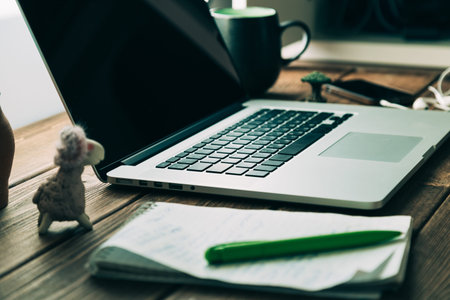 Workplace with open laptop on modern wooden desk, angled notebook on table in home interior,...