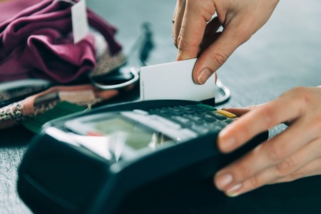 hand swiping credit card on terminal in storeの写真素材