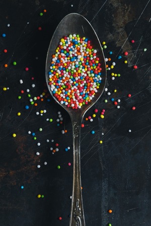 Colorful Sugar Balls in vintage spoon on dark grunge metal background, top view.の写真素材