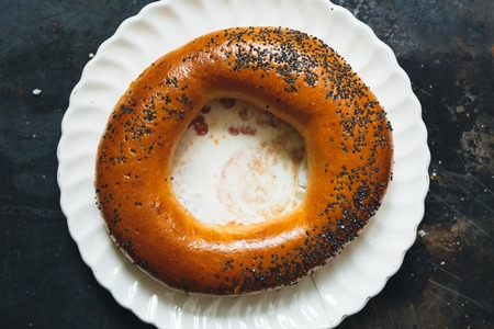 Bagel with poppy seeds on the plate on dark grunge metal background, top view.の写真素材