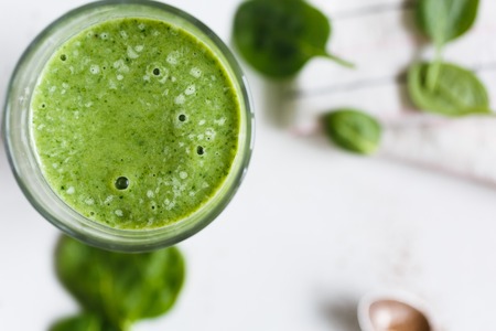 Green smoothie with banana and spinach, fresh herbs on the background, top viewの写真素材