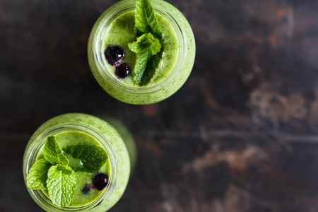 Two green smoothie with banana and spinach, fresh herbs on the dark background, free copyspace for design,  top viewの写真素材
