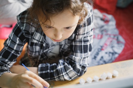 eight year old girl in a plaid shirt with enthusiasm that paints with a brushの写真素材