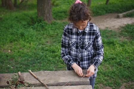 eight year old girl in a plaid shirt plays one on the street with a rope and stone in the summerの写真素材
