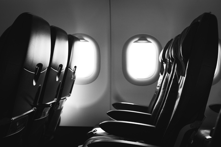 Black and white photo of airplane seat and window inside an aircraftの写真素材