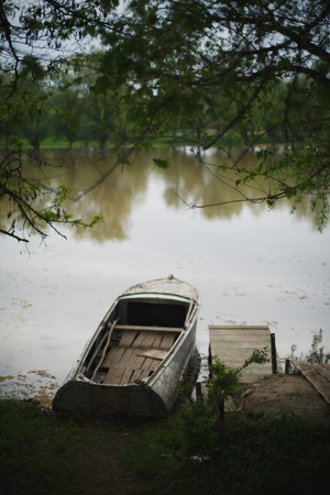 a blue boat moored to the banks of the riverの写真素材