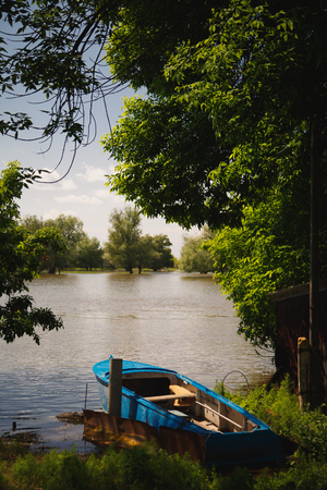 a blue boat moored to the banks of the riverの写真素材