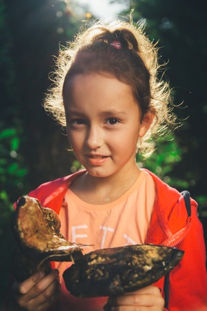 girl holding in hands the big mushrooms and looking at the camera on a summer dayの写真素材