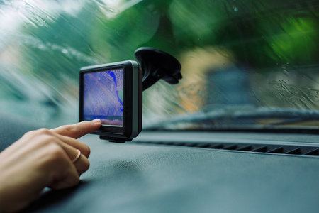 woman looking road on the map GPS Navigator sitting behind the wheel of a car on a rainy dayの写真素材