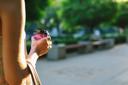 woman walks down the street and drinking coffee from a paper Cup on a summer dayの写真素材