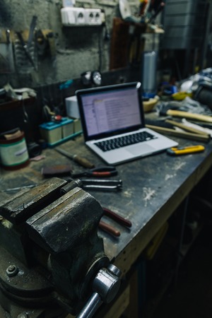Above view of used hammer,pliers and chisel with laptop and smartphone on metal tableの写真素材
