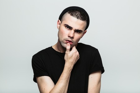 Studio portrait of sensual and thinking man looking at camera posing with hand on chin.の写真素材