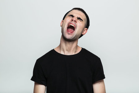 Studio shot of an annoyed man screaming, his head tilted back