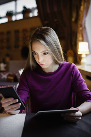 Serious woman looking at smartphone. Vertical indoors shot. 