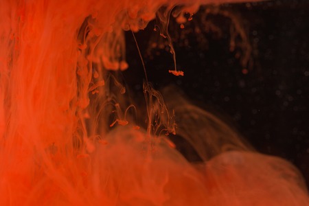 Red paint on the dark background doing stains because of drop into water. Looks like blood.の写真素材