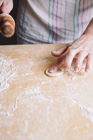 Close-up image of two womans hands making dough for meat dumplings.の写真素材